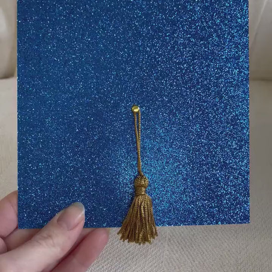 a video of the shimmery blue glitter graduation cap invitation with a real gold tassel 