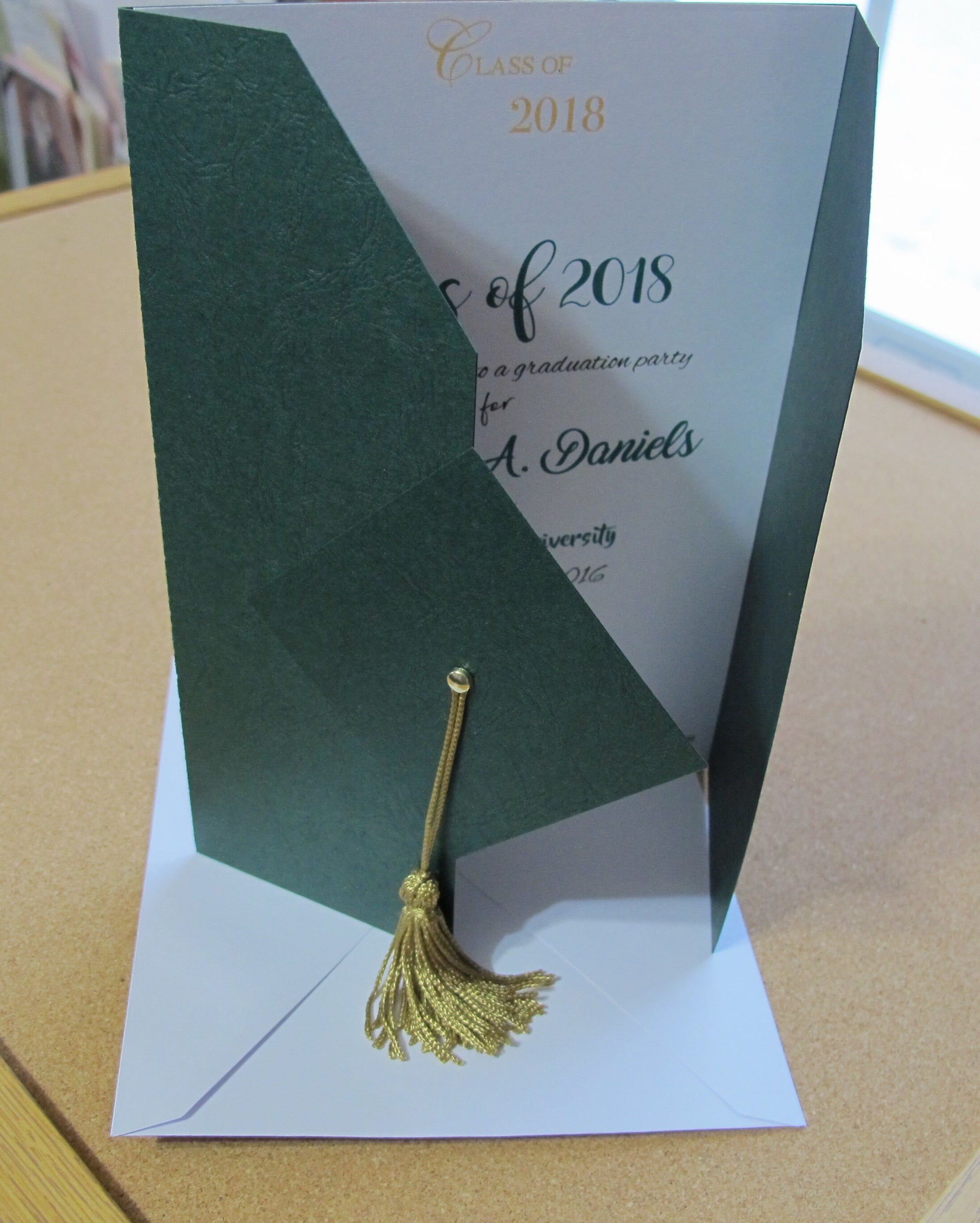 hunter green graduation gown and cap shaped invitation