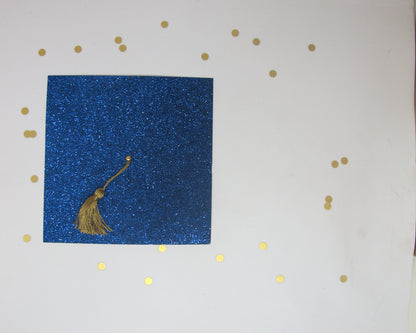 A blue glitter graduation cap invitation with a real gold tassel on a white background