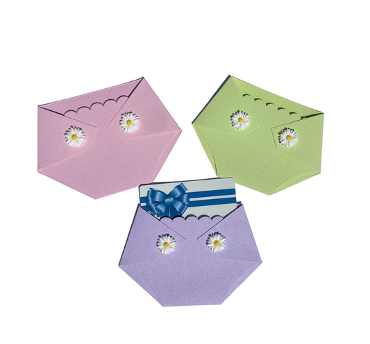 three diaper shaped gift card holders in pink, green, and purple with white daisies on the diaper flaps