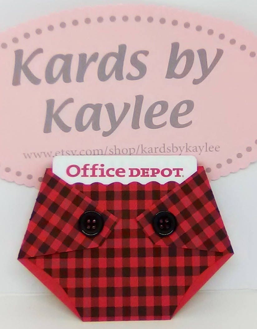 A plaid-patterned, diaper-shaped gift card holder with a red and black checkered design and black buttons, designed to hold a standard gift card.