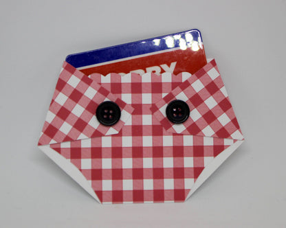 A plaid-patterned, diaper-shaped gift card holder with a red and white checkered design and black buttons, designed to hold a standard gift card.